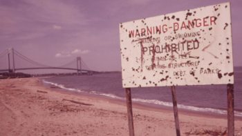 Warning of polluted water at Staten Island Beach, Verrazano-Narrows Bridge in the background, June 1973. | Arthur Tress/EPA